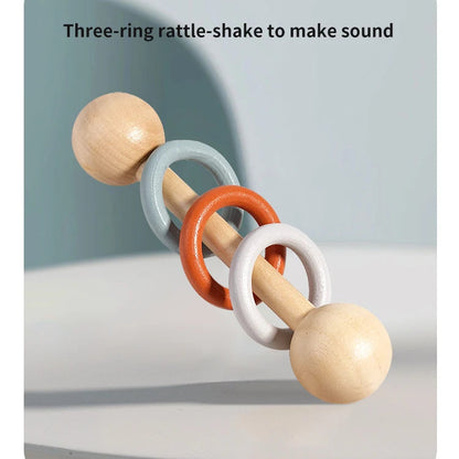 Wooden rattle-shake toy with three colored rings on a light gray background